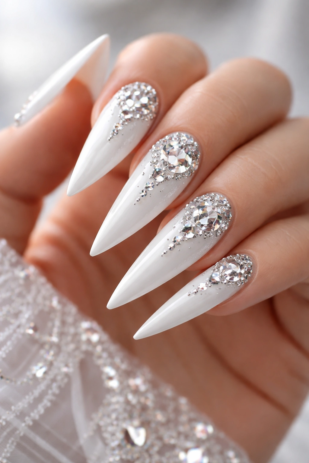 White stiletto nails with diamond embellishments arranged in a deliberate pattern