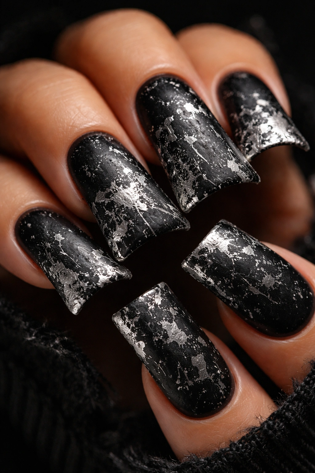 Duck nails with distressed black polish and silver splatter.