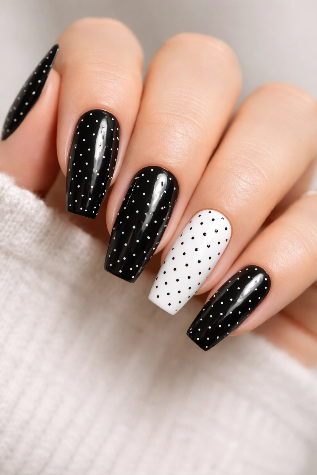 Black nails with tiny white dots and one inverted white nail with black dots