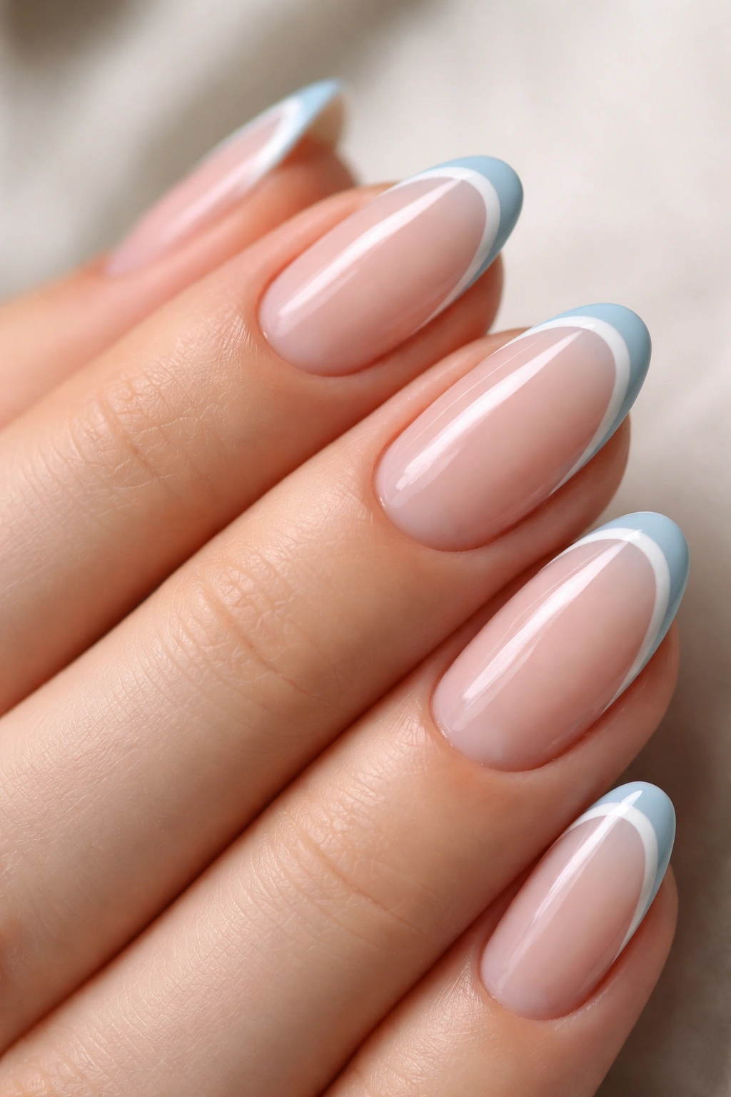 Close-up of short almond nails with light blue and white double French lines