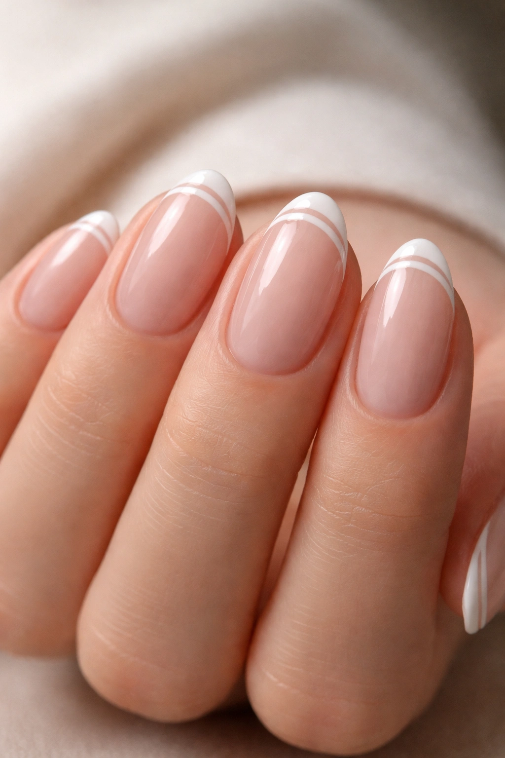 Close-up of double slim French lines on almond nails with a tiny gap.
