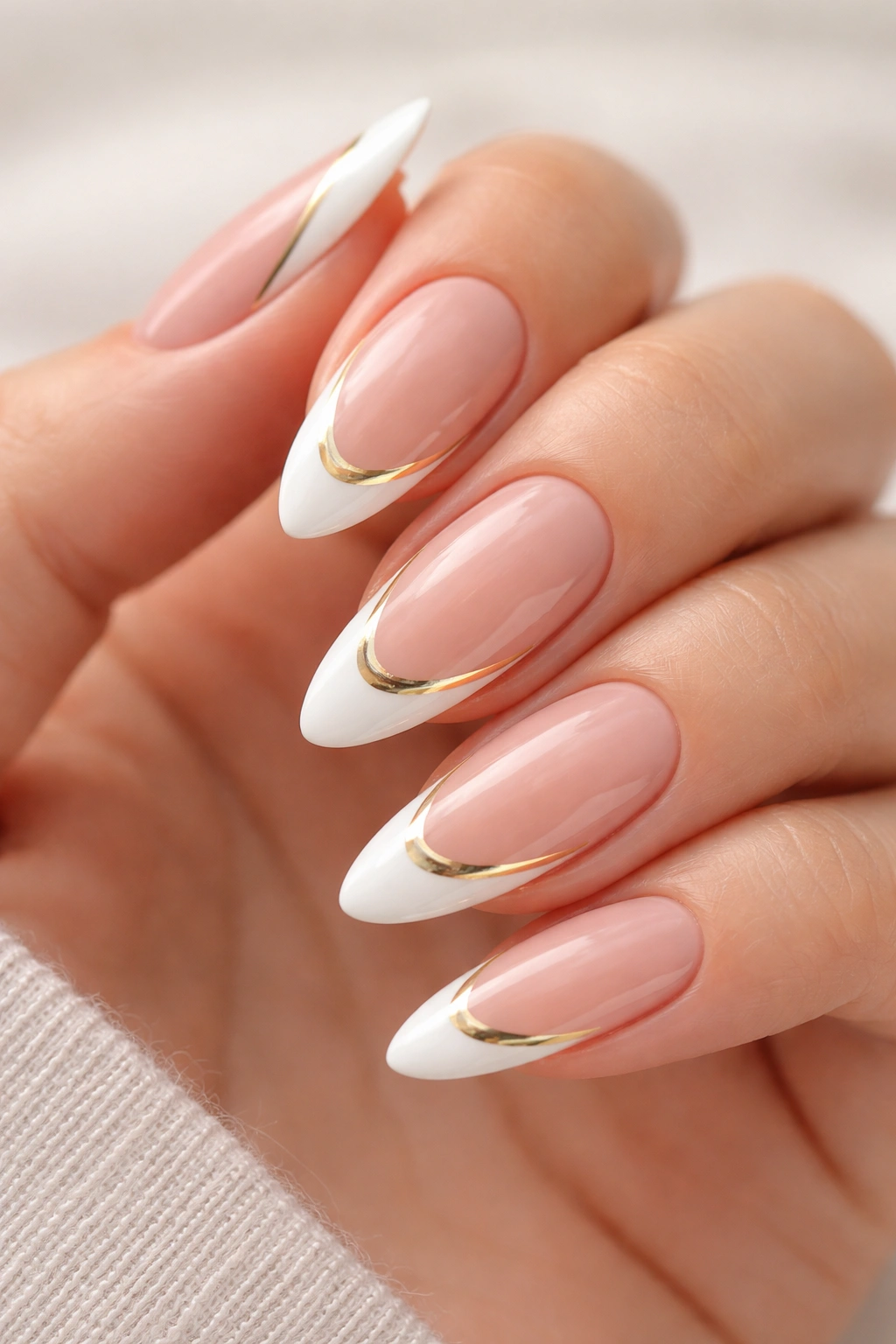 Close-up of almond nails with sheer nude base, white tip and thin gold line