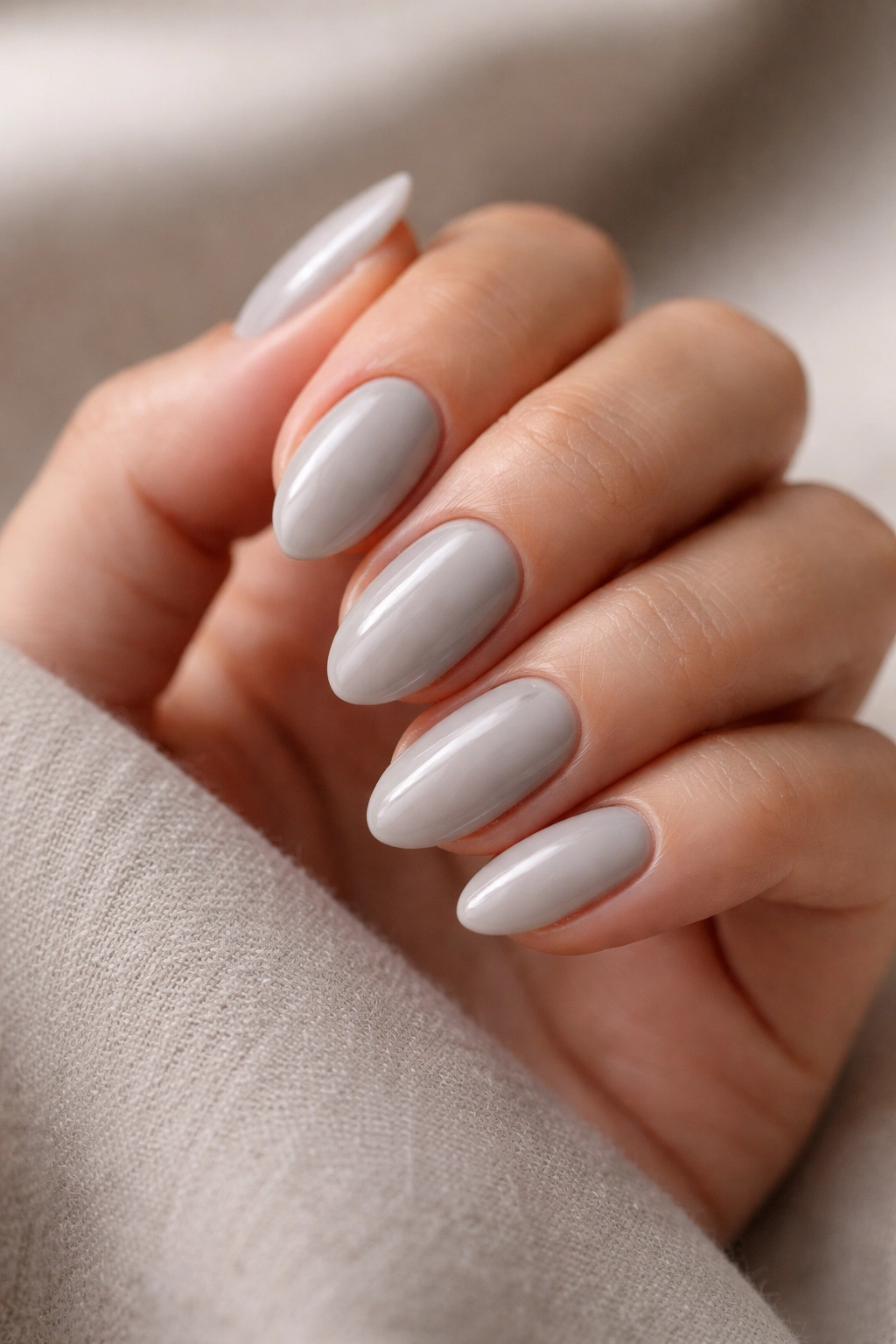 Close-up of short almond nails in soft dove grey with a glossy finish