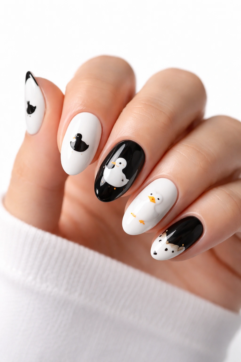 Close-up of black-and-white duck nail art on a hand with a minimalist high-contrast manicure