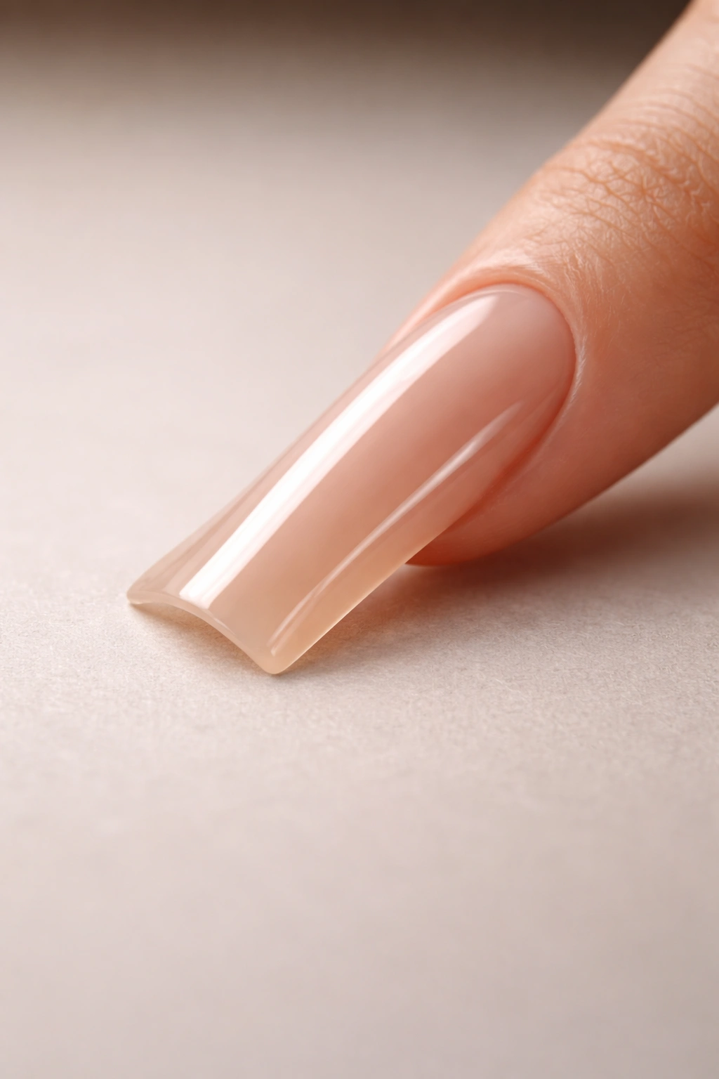 Close-up of a single long duck nail on a neutral surface