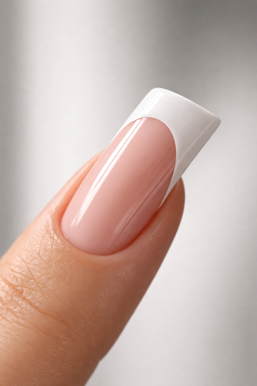 Close-up of a single duck nail with white French tip on neutral gray background