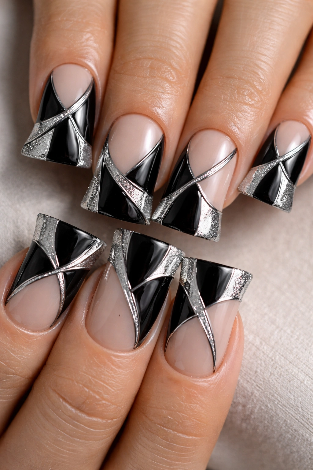 Duck nails showing black and silver negative space patterns on pale base