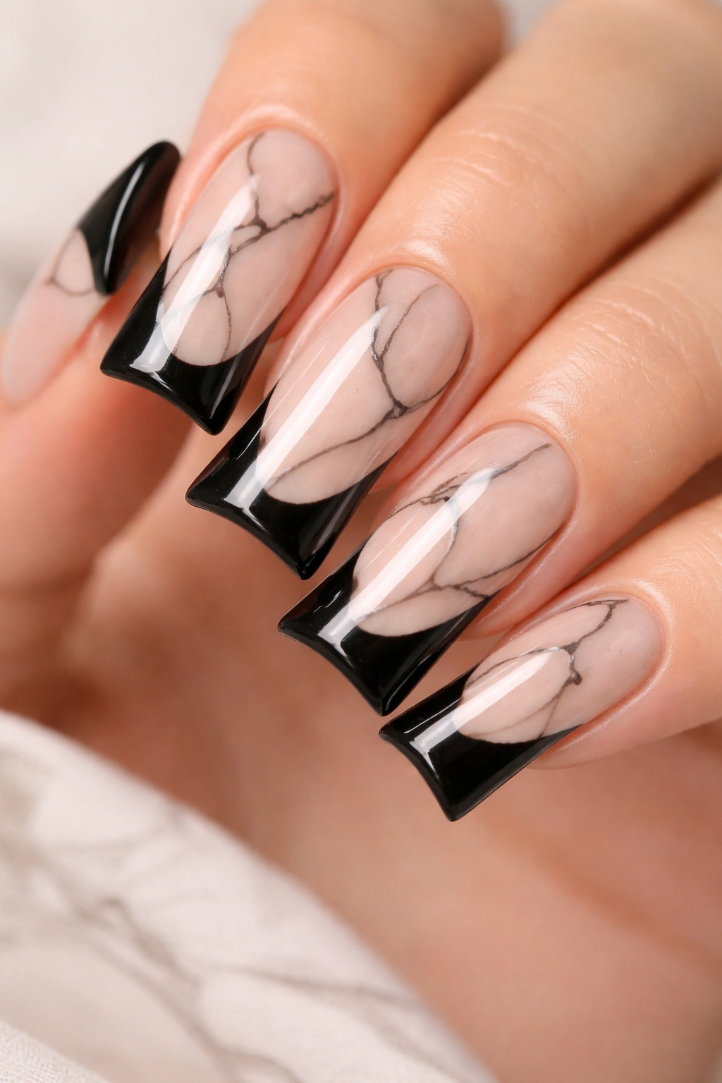 Close-up of duck nails with nude marble effect and black lines
