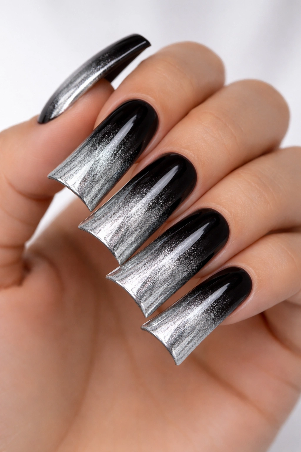 Close-up of duck nails with black to silver ombre gradient on long nails