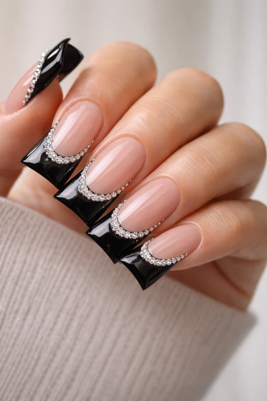Close-up of duck nails with black French tips and a rhinestone accent line on a neutral background