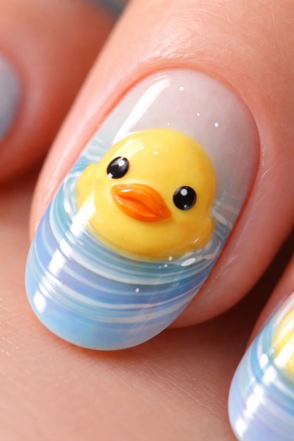 Close-up of yellow duck face nail art with blue and purple water ripple details on a glossy nail