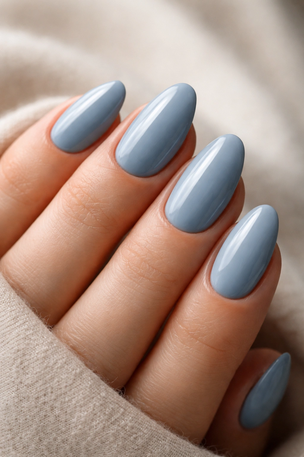 Close-up of dusty blue almond nails with a cream finish on short nails.