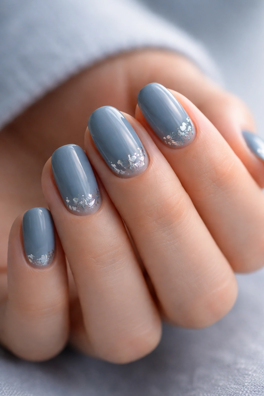 Dusty blue nails with silver foil accents on short oval nails