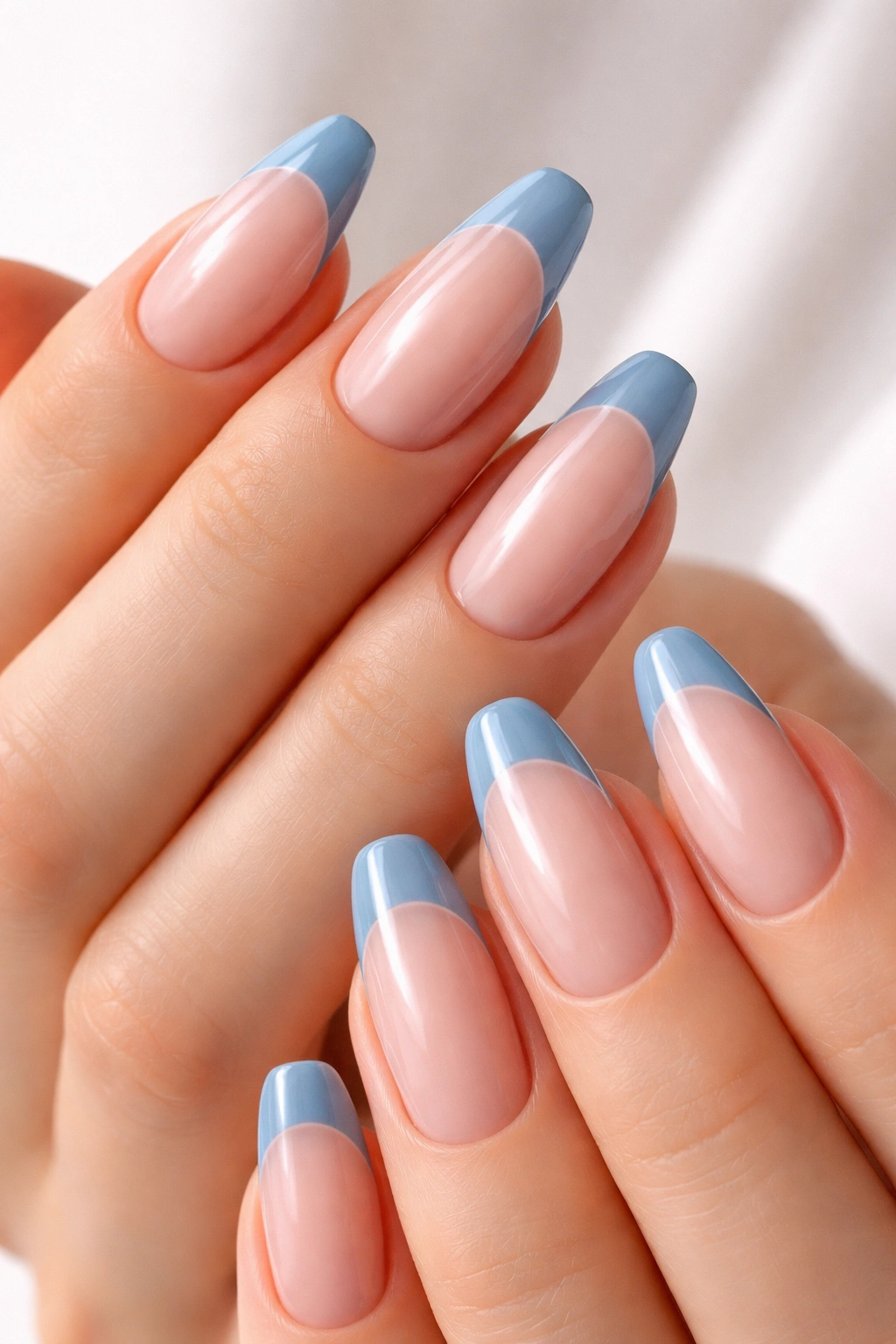 Close-up of hands with dusty blue French tips on nude base, precise lines