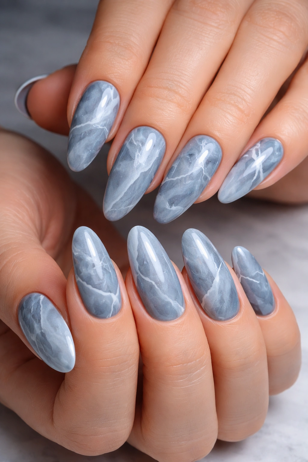 Close-up of dusty blue marble nails with white and gray veining