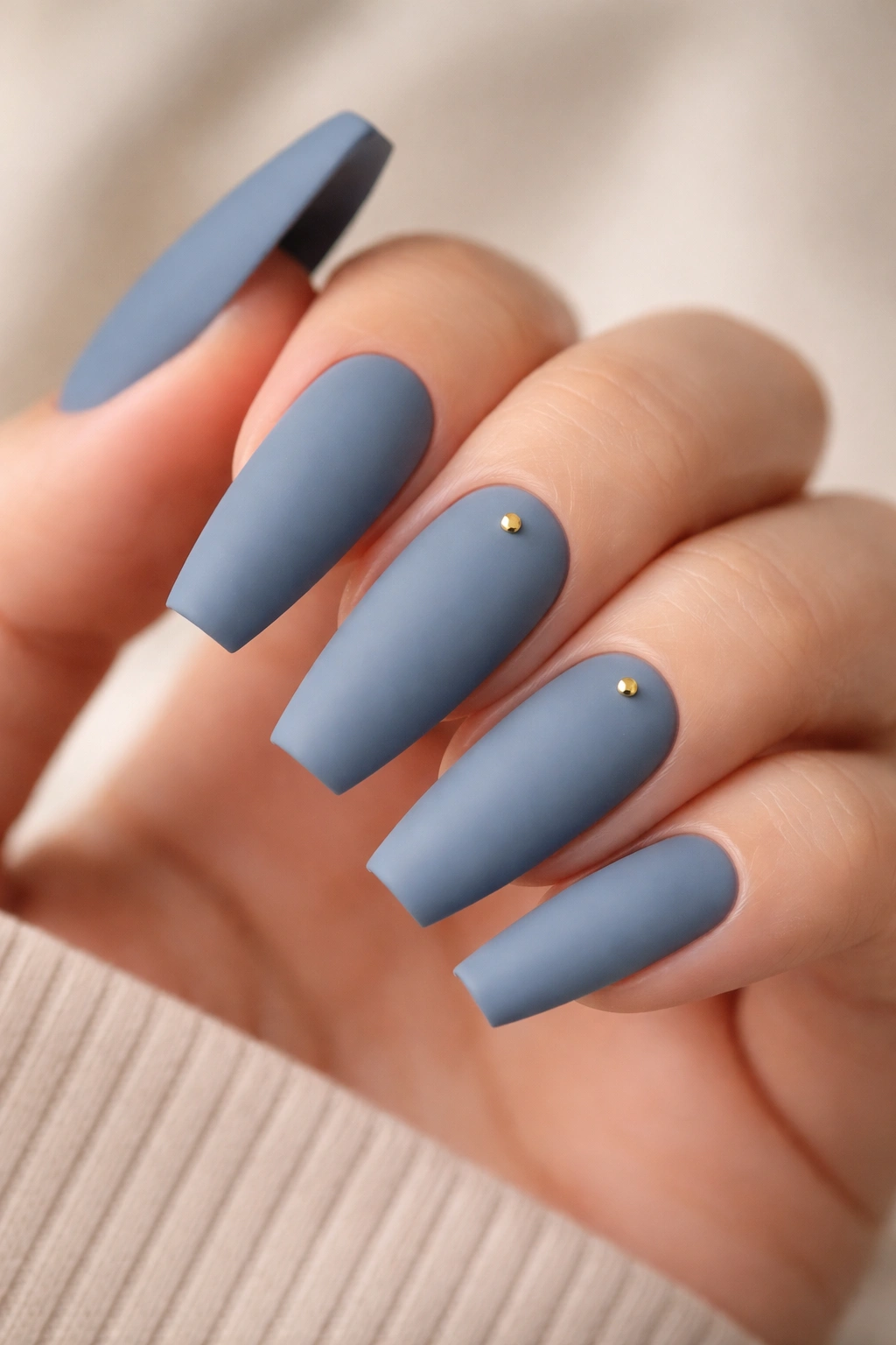 Matte dusty blue nails with small gold studs on accent nails
