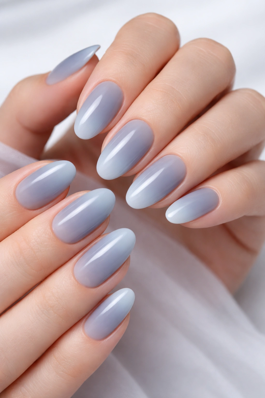 Close-up of dusty blue ombre nails fading to pale blue