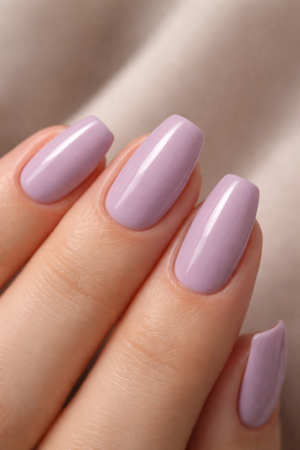 Close-up of a short tapered nail in dusty lilac cream with glossy finish