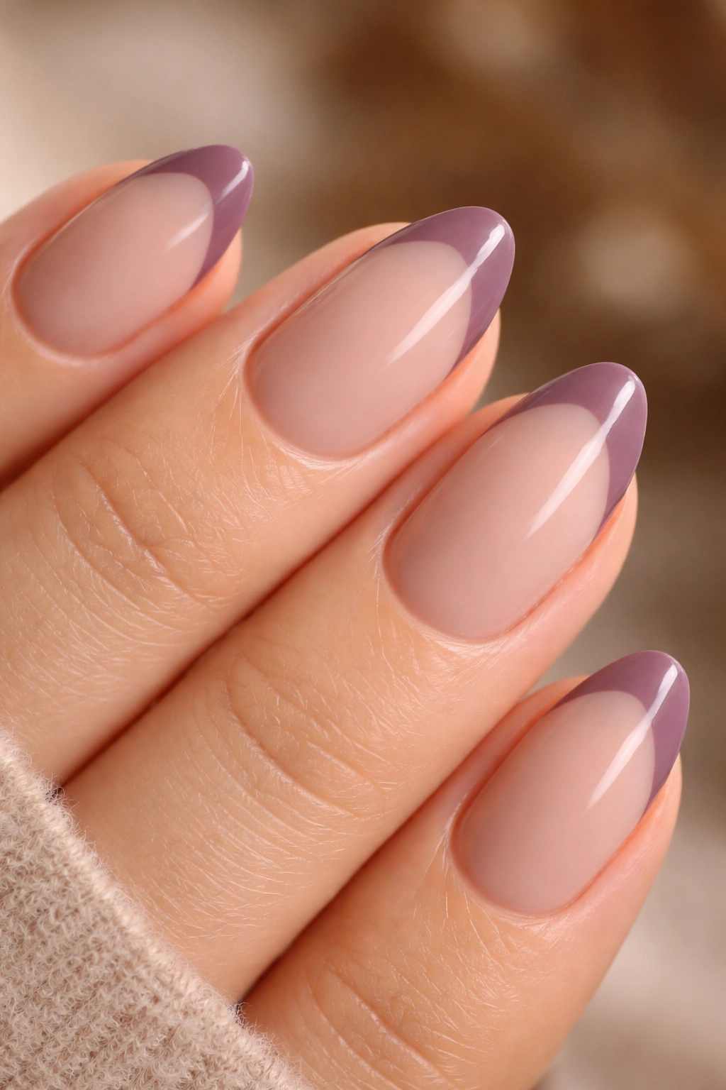 Close-up of a dusty mauve French tip on a warm nude base on a short almond nail