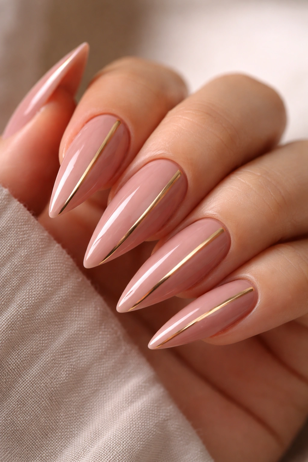 Close-up of dusty pink nails with thin gold stripes