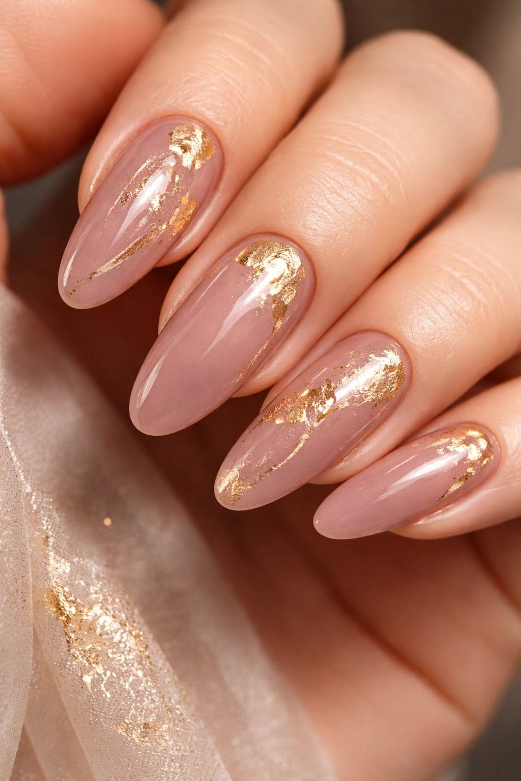Long oval nails with dusty rose base and gold foil accents, high-gloss finish