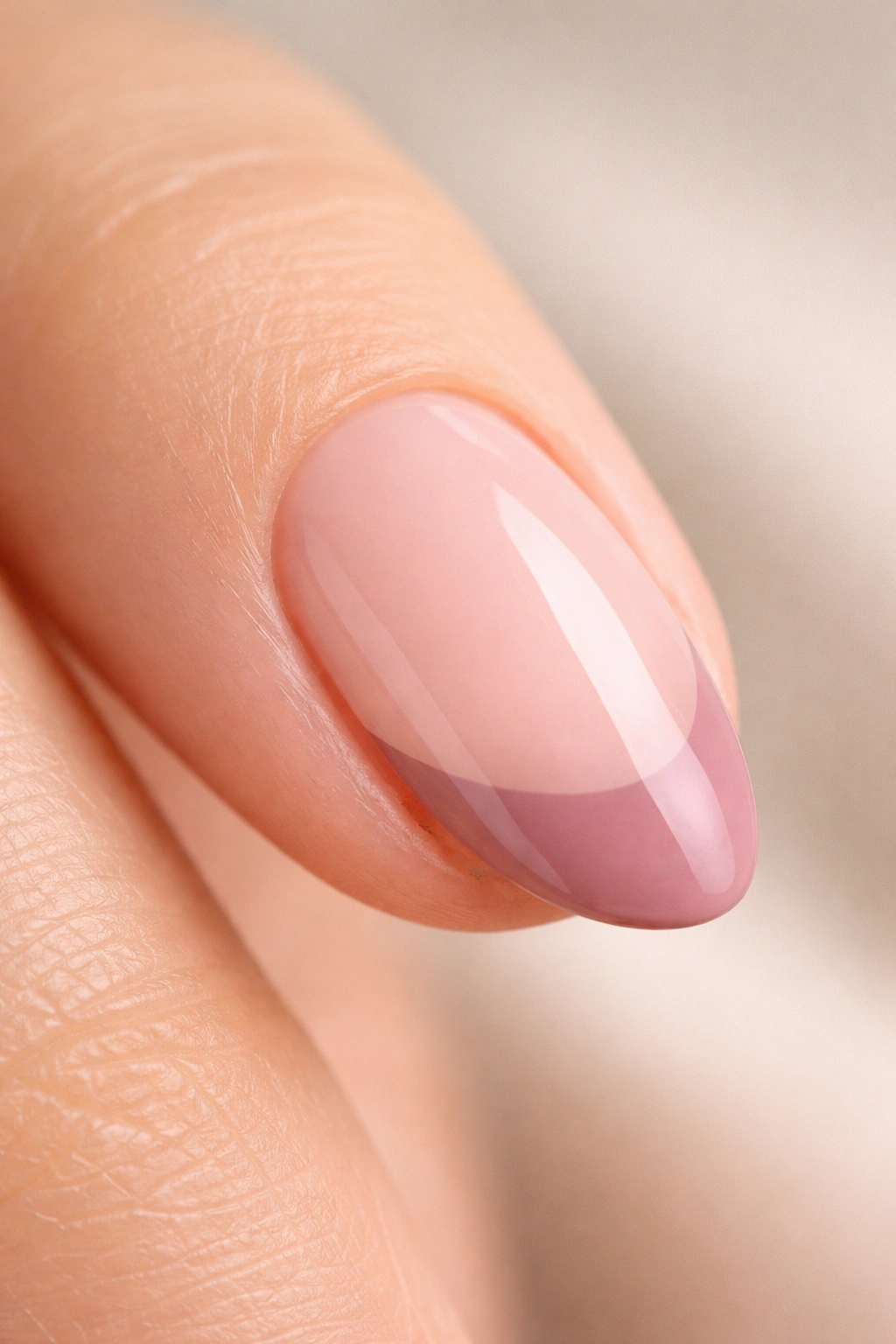 Close-up of a short almond nail with dusty rose tip on translucent pink base