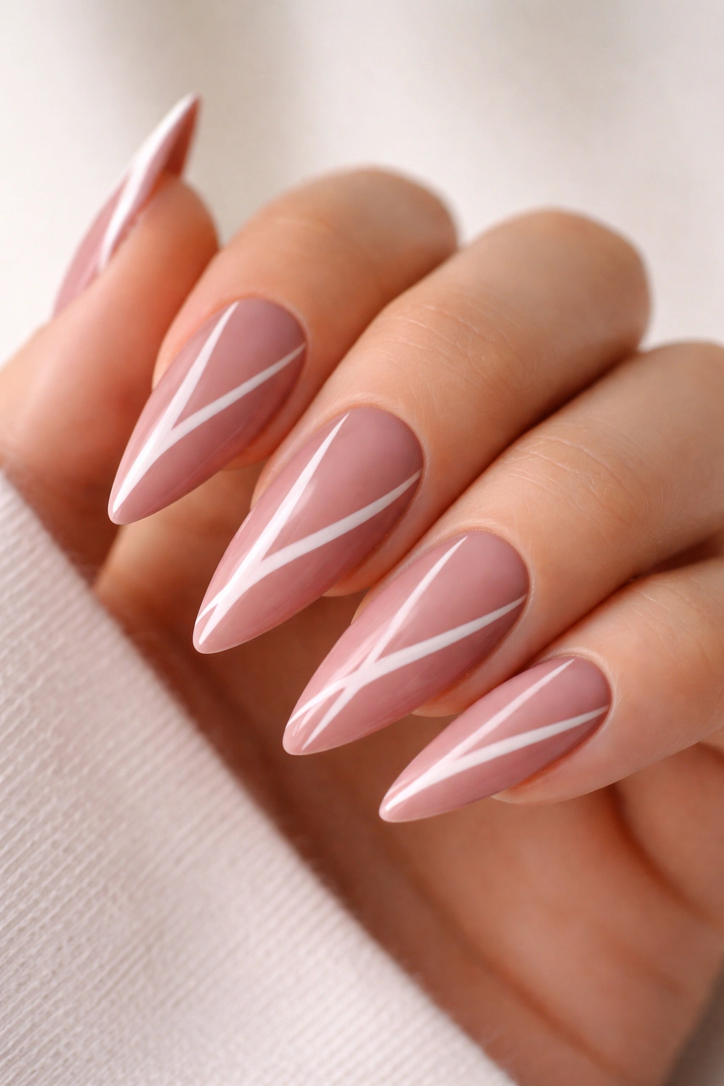 Dusty rose stiletto nails with white negative-space lines on medium-length nails