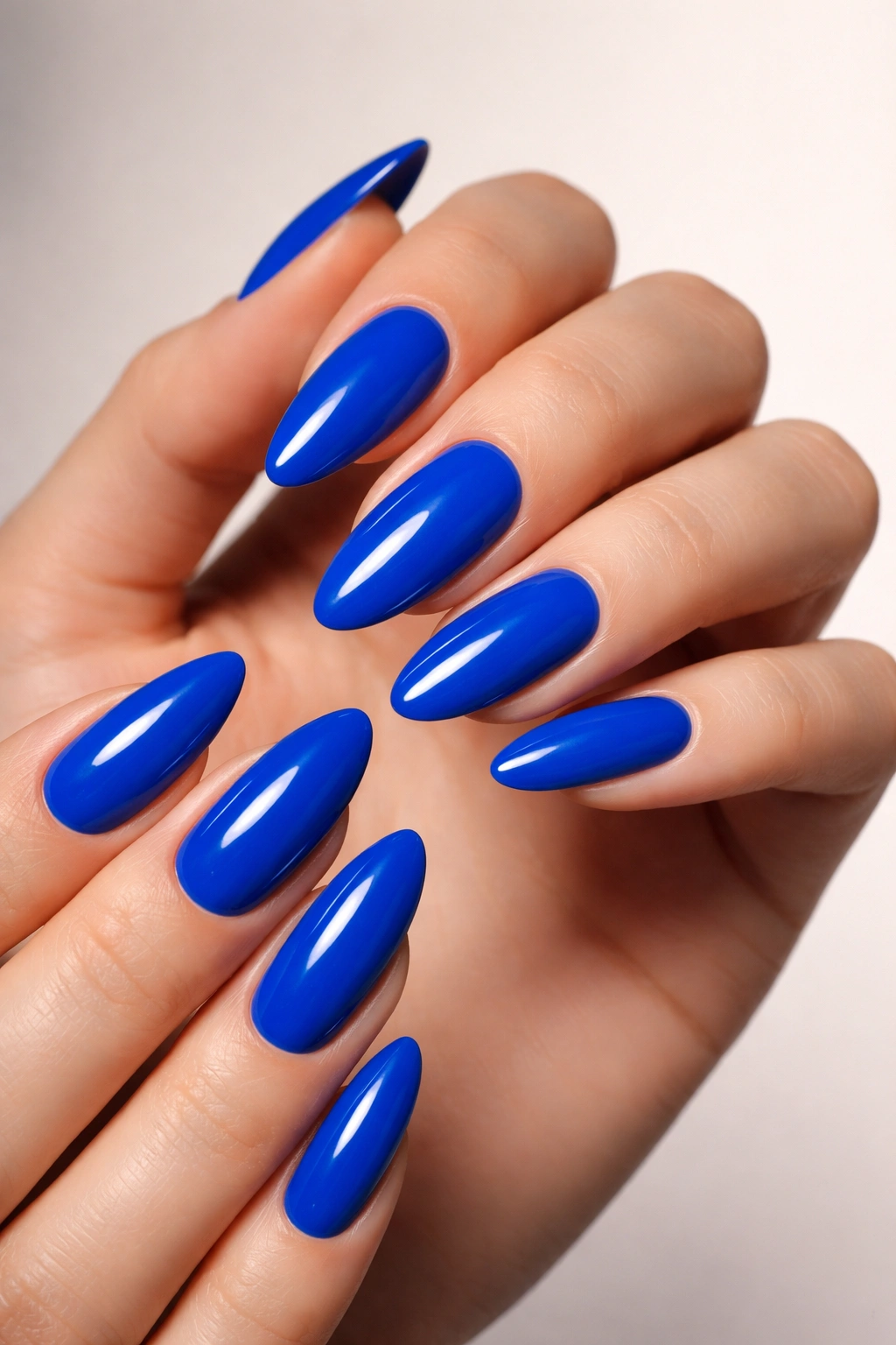 Close-up of nails painted electric blue on hands with a clean background