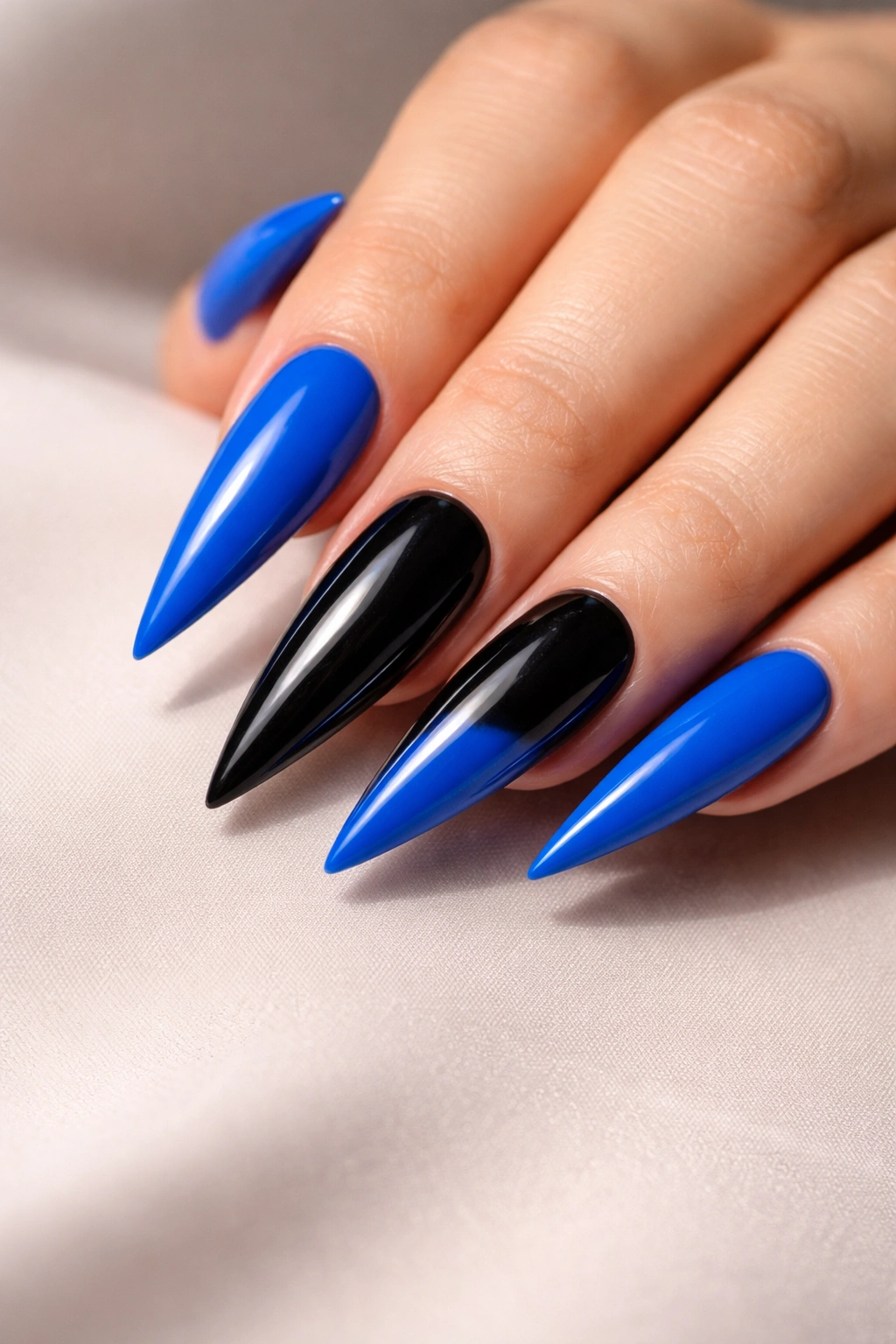 Close-up of electric blue stiletto nails with black accent nails on a hand