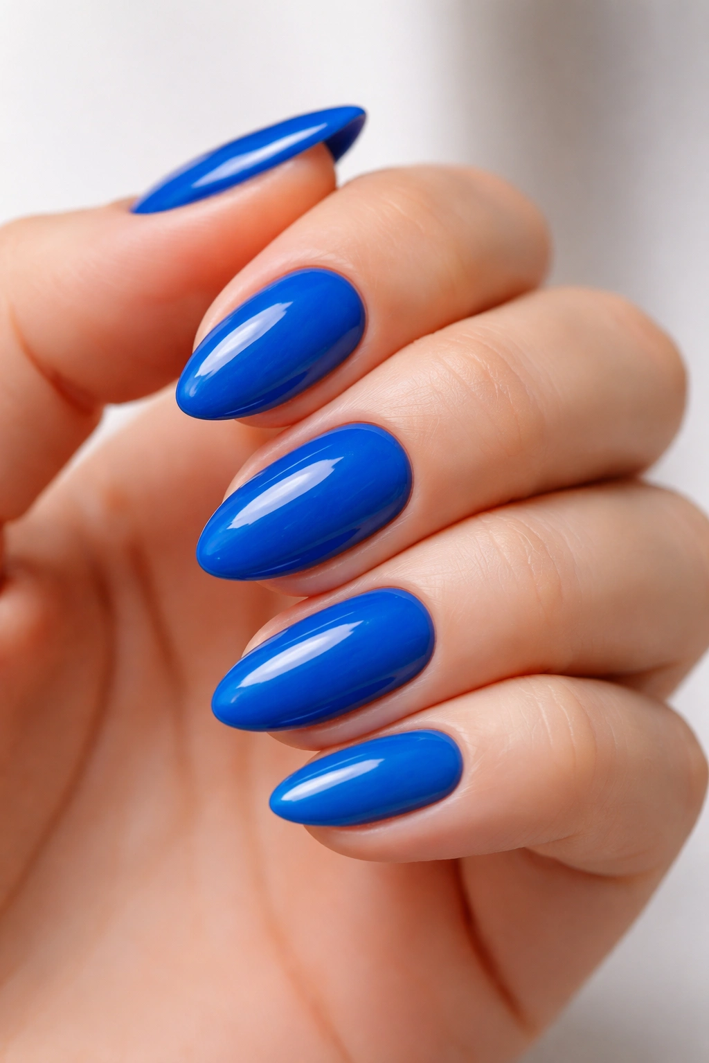 Close-up of electric blue nails on a short almond shape with a glossy finish