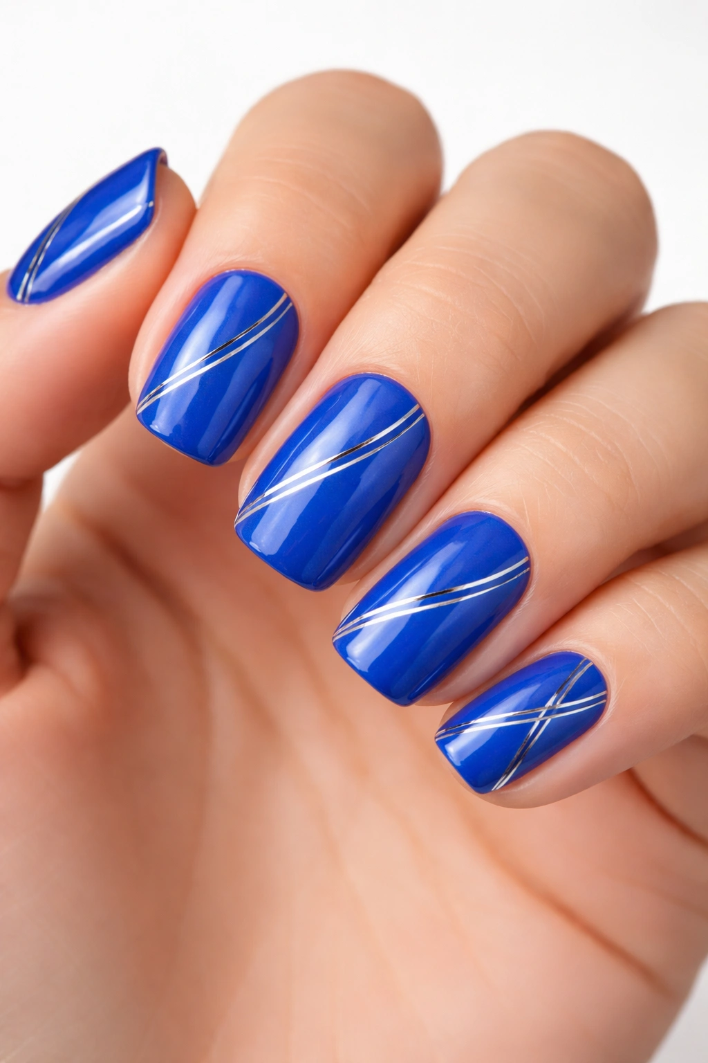 Close-up of electric blue squoval nails with silver striping