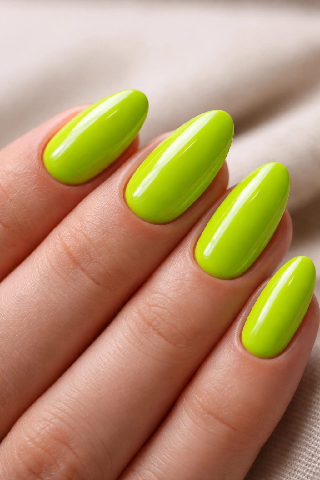 Close-up of short almond nails in electric lime neon with glossy finish