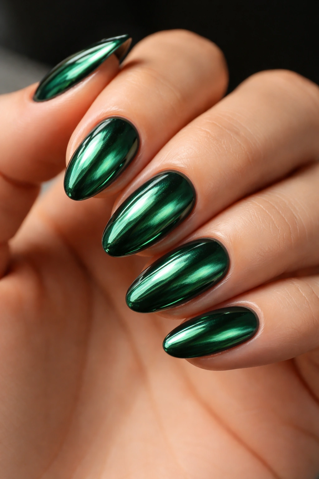 Close-up of short almond nails with emerald chrome finish
