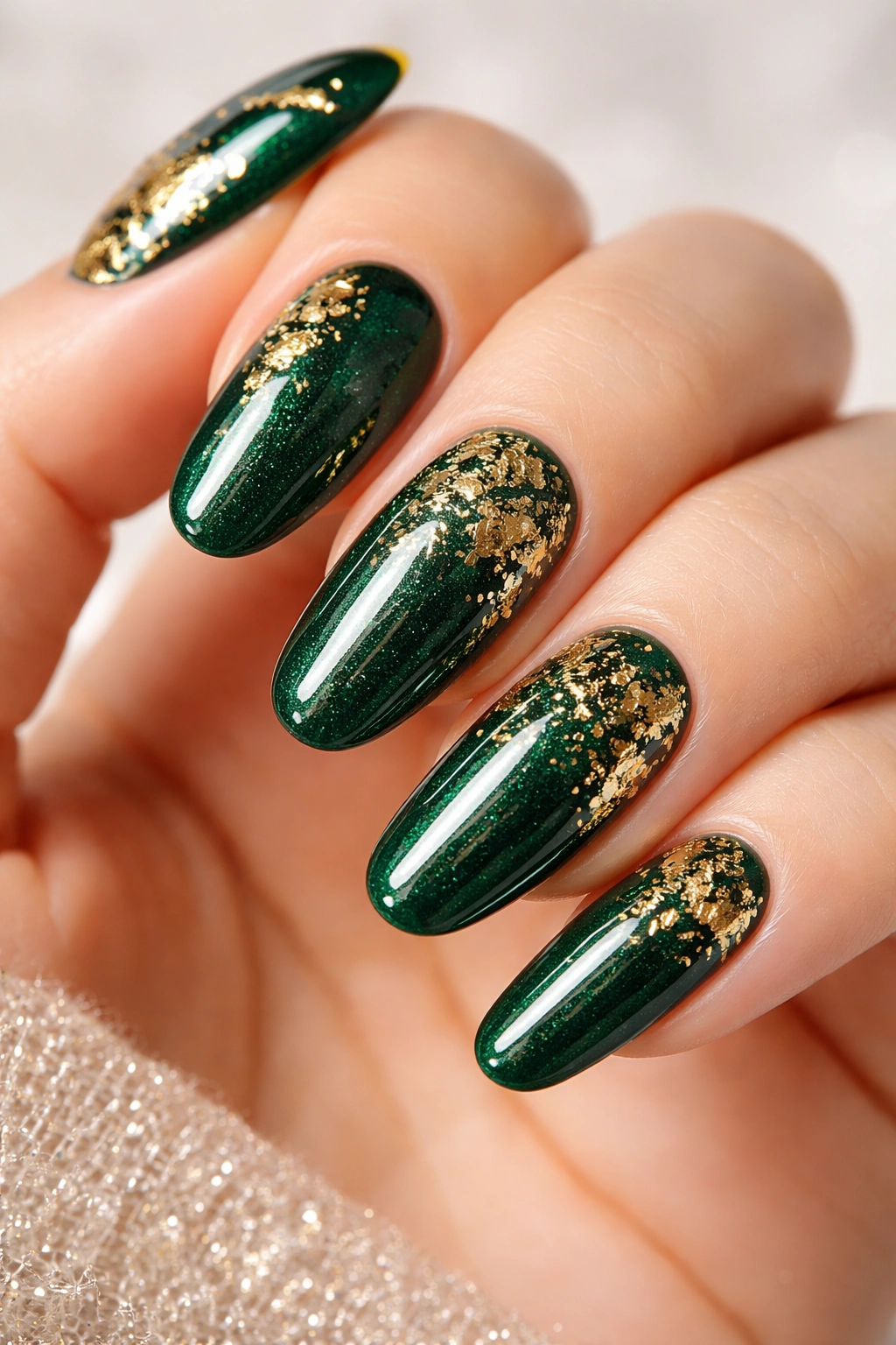 Emerald green nails with gold foil accents on long round nails, textured finish.