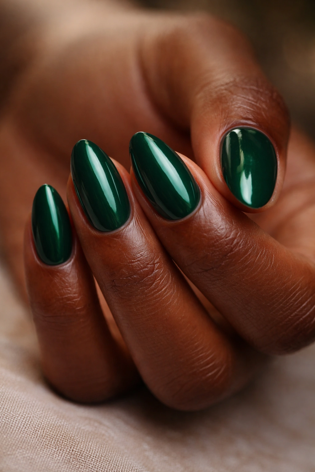 Close-up of emerald green short almond nails on a hand