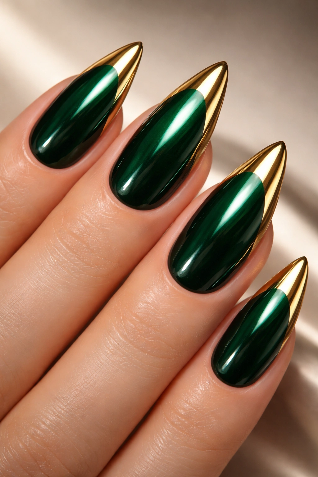 Close-up of emerald green nails with gold chrome tips