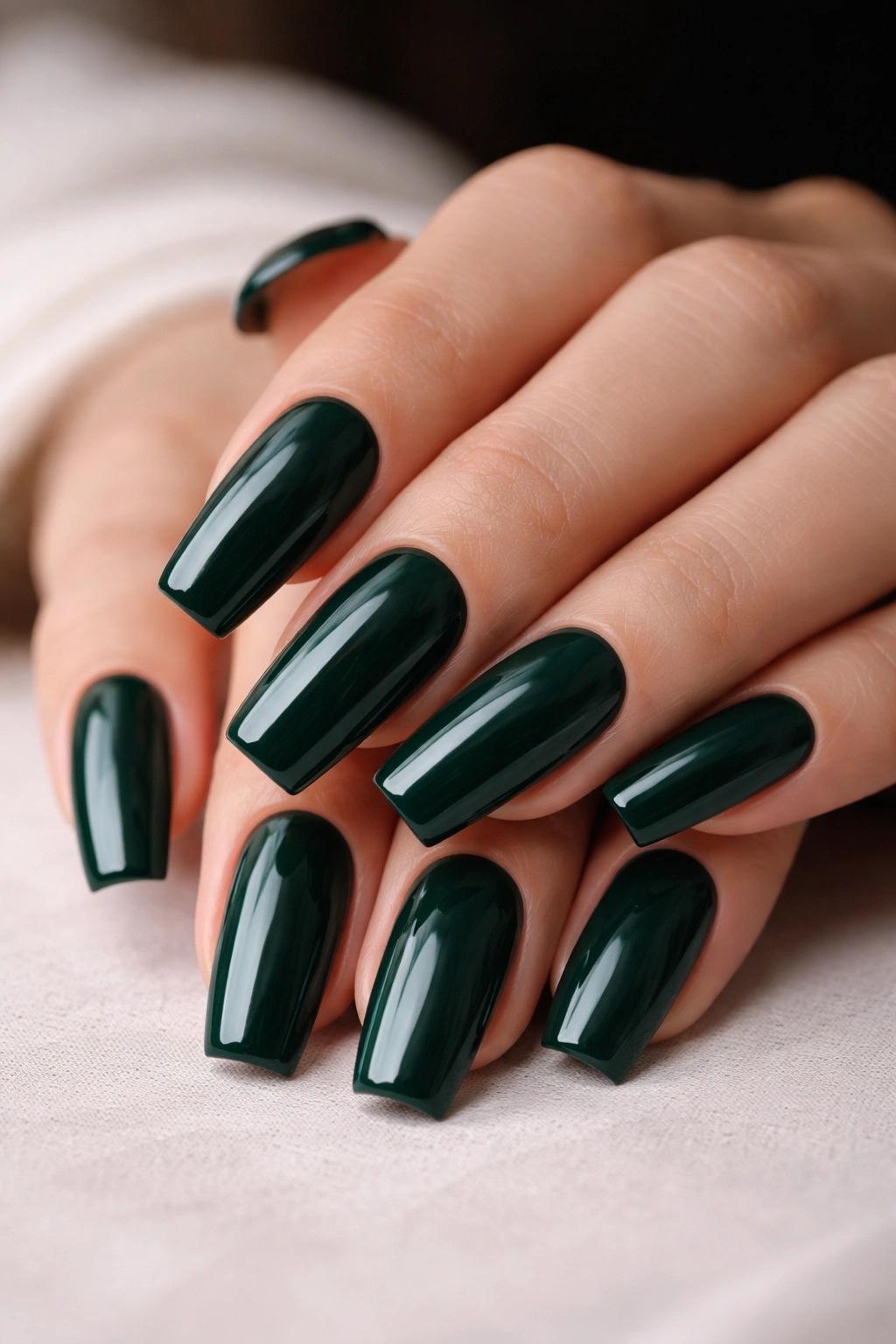 Close-up of medium coffin nails in deep emerald green cream finish
