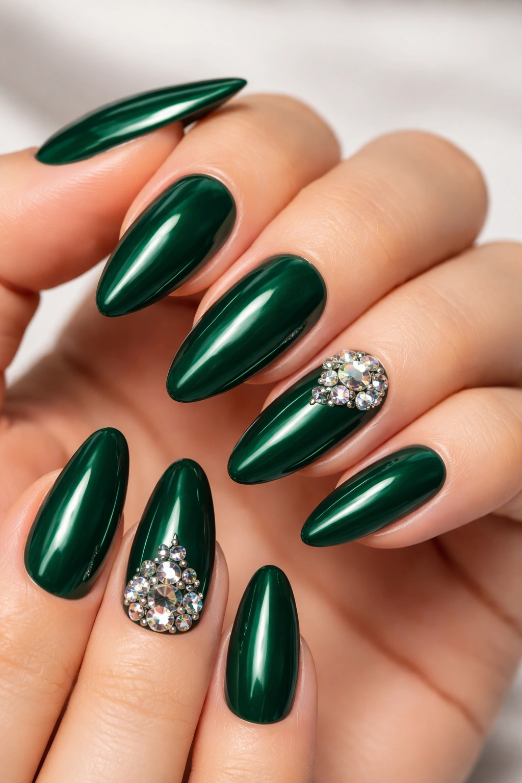 Close-up of emerald green nails with crystal accents on almond-shaped nails