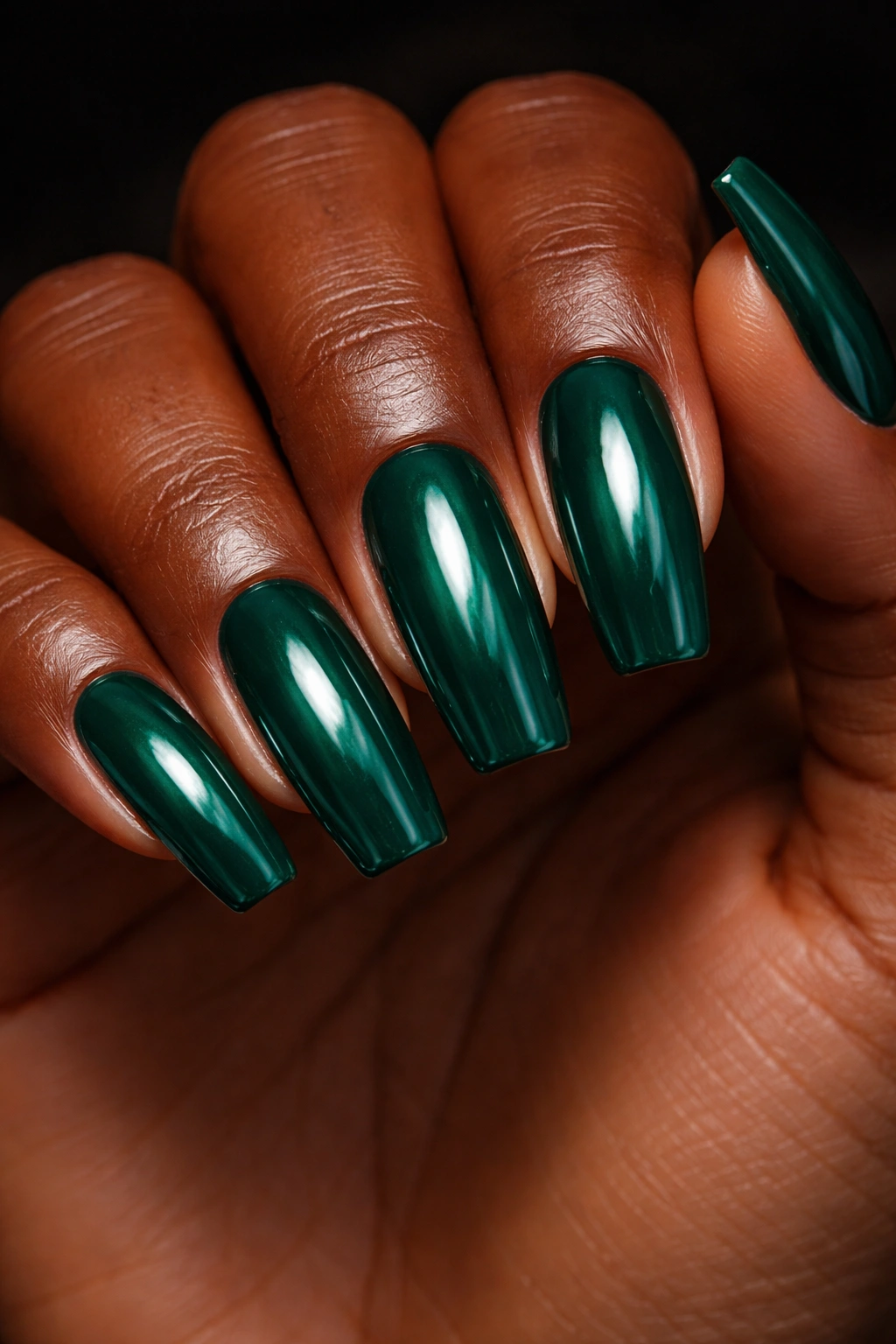 Close-up of dark-skinned hand with emerald green nails, high-gloss finish