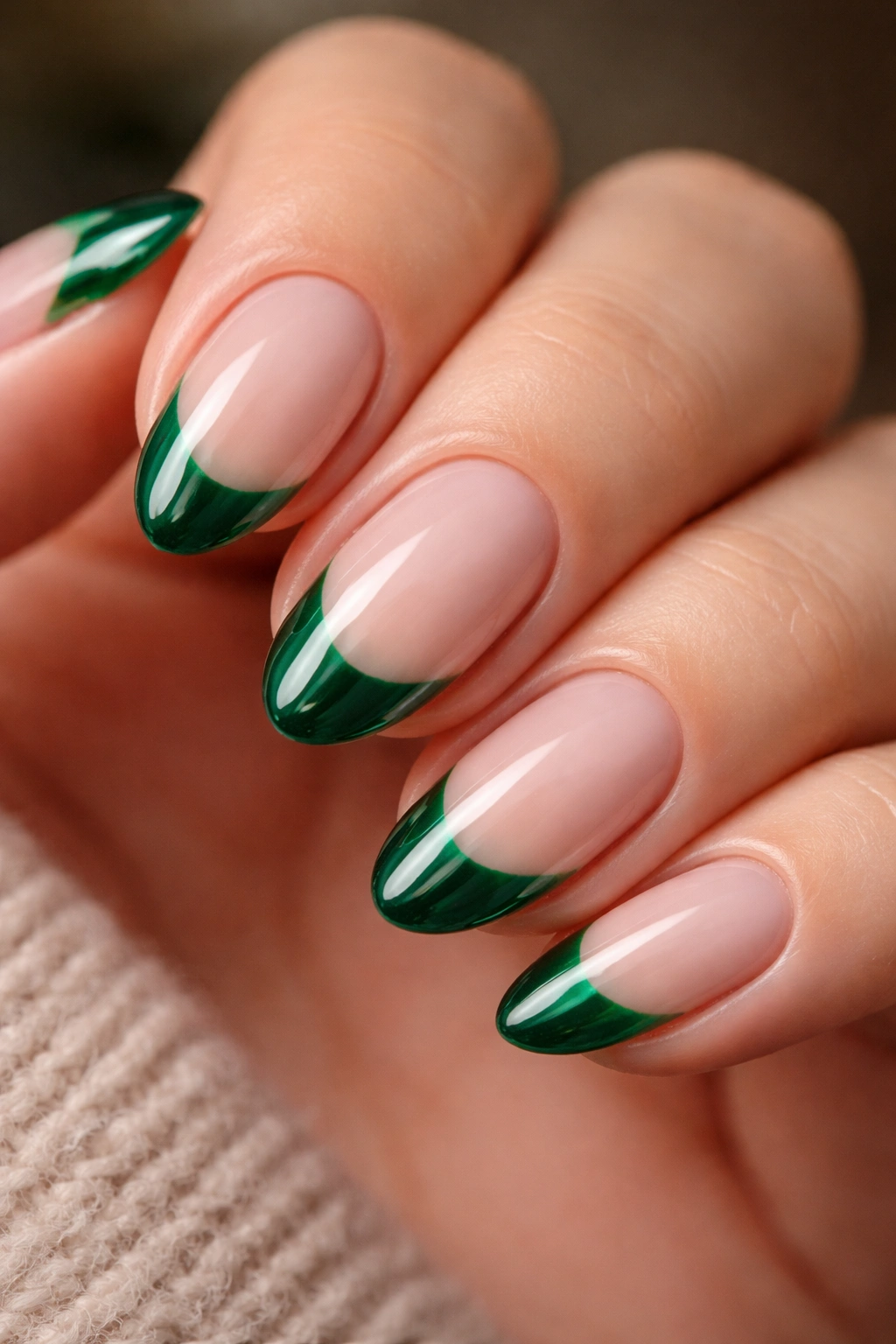 Close-up of short almond nails with emerald green tips under high-gloss gel finish