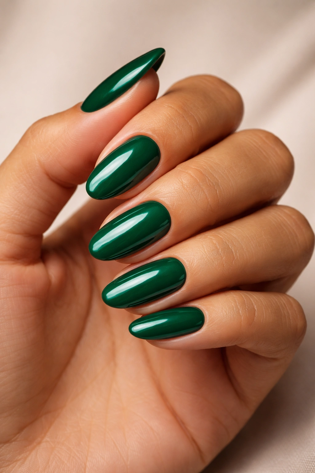 Close-up of emerald green nails on olive skin.