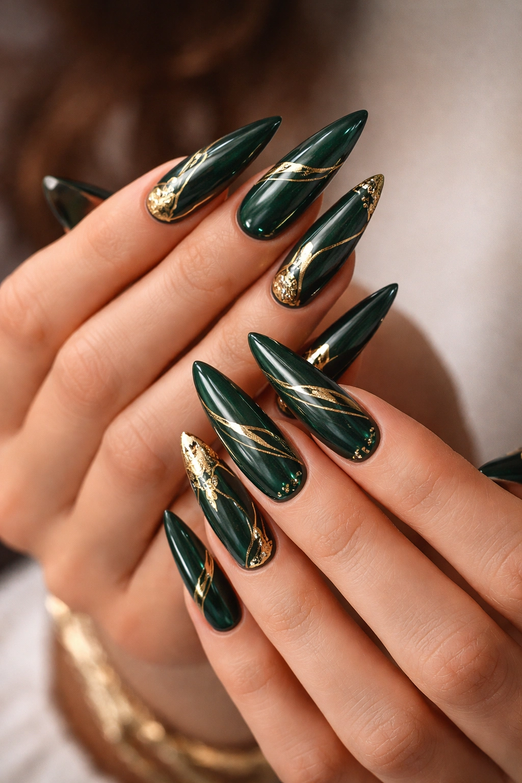Close-up of emerald green stiletto nails with metallic gold details