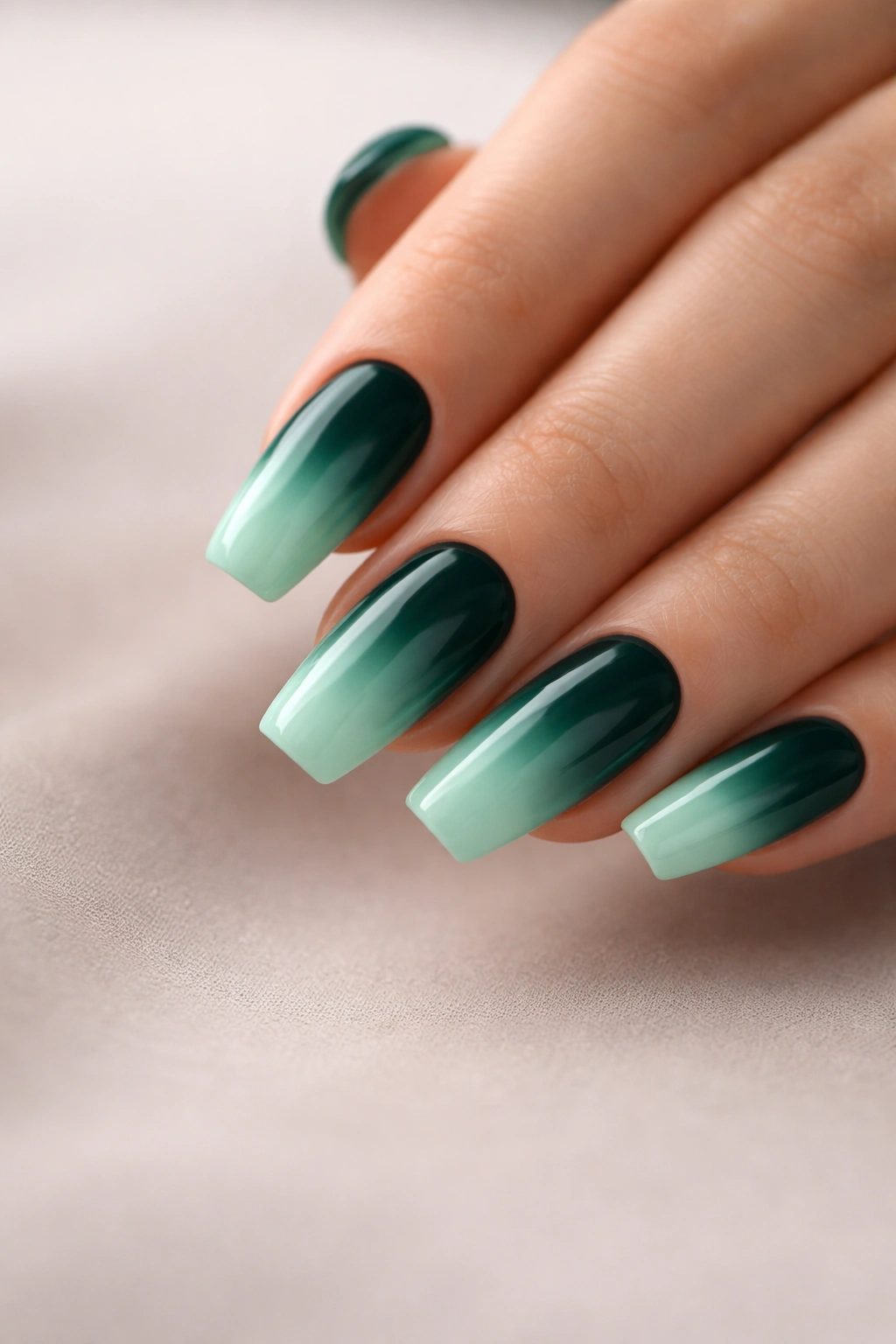 Close-up of emerald green to mint ombre nails on medium coffin shape with glossy finish