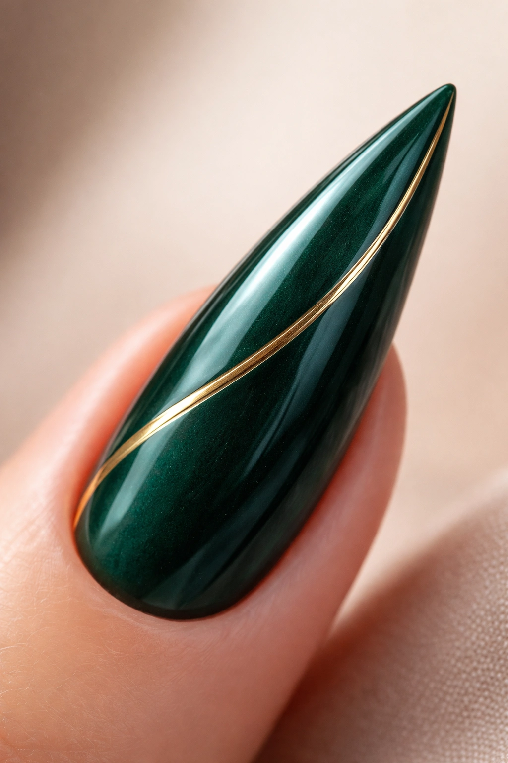Close-up of a deep emerald curved stiletto nail with a gold geometric accent along the curve