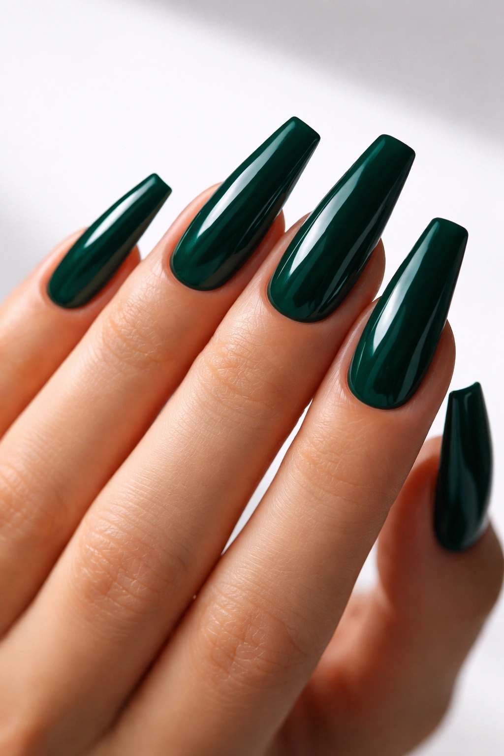 Close-up of emerald ballerina nails with a high-gloss finish on a bare hand