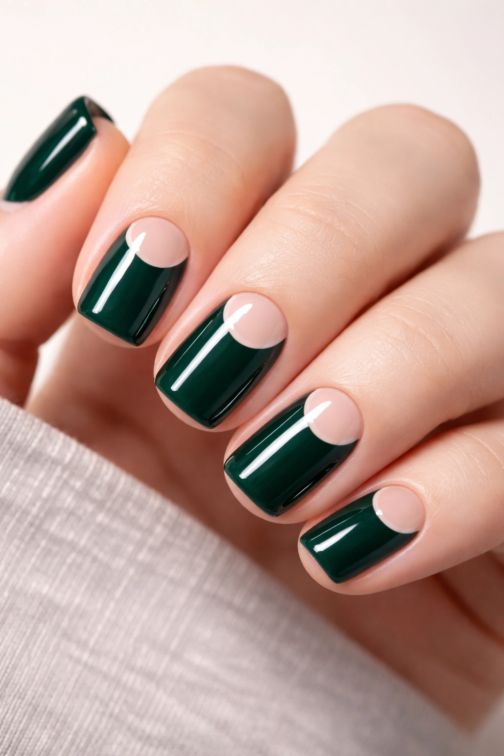 Close-up of short squoval nails featuring emerald base with negative space moon