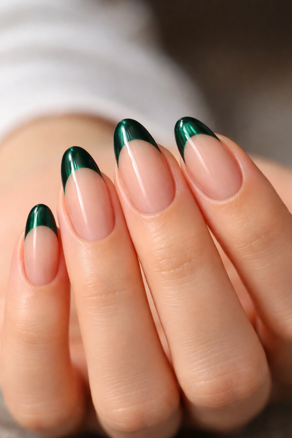 Close-up of short almond nails with emerald tips and bare nail space