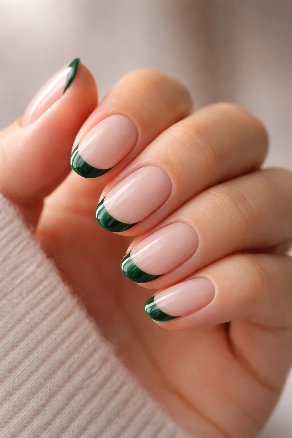 Close-up of short oval nails with emerald tips on milky pink base
