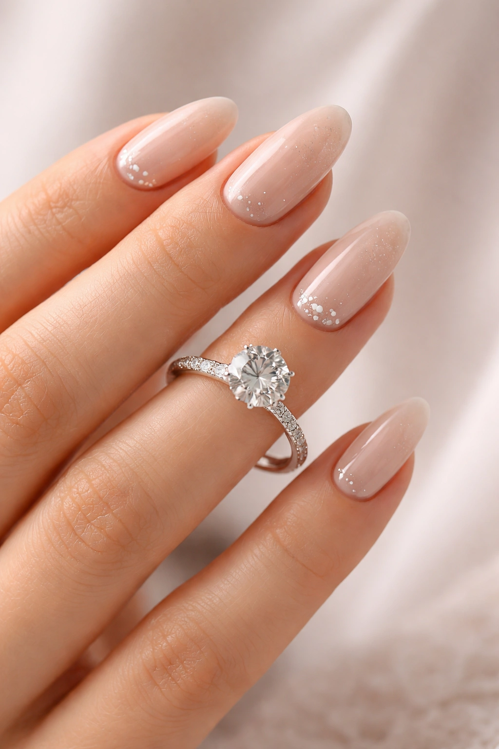 Close-up of an elegant engagement manicure framing a ring on the finger with soft lighting