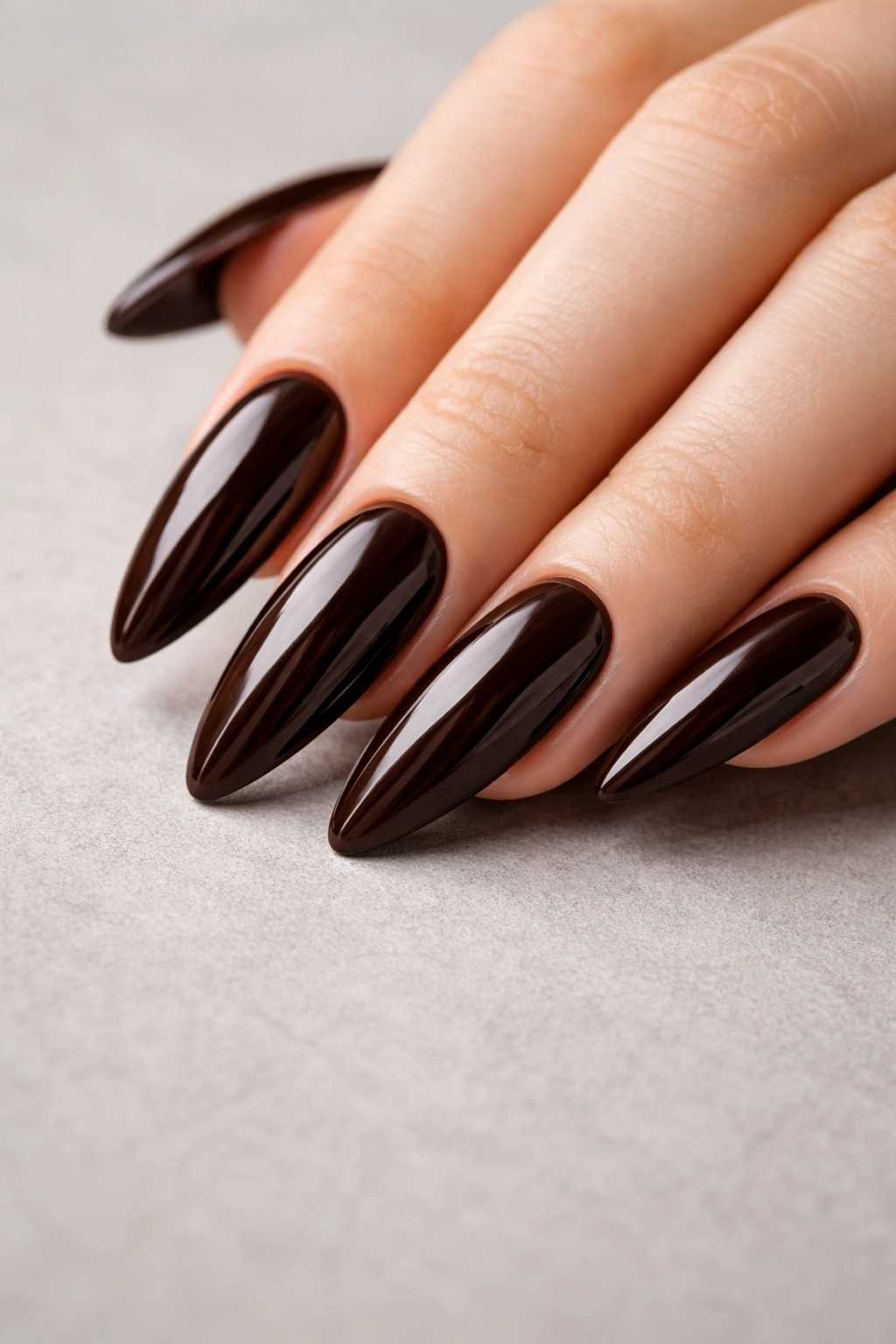 Close-up of glossy espresso almond nails showing depth and shine